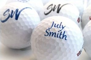 Custom-printed golf balls with the name “July Smith” and the initials “SW.”